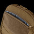 Close-up of the Condor LCS Tidepool Hydration Carrier, a tan backpack with military-inspired design, partially unzipped to reveal its patterned gray interior lining and rugged fabric construction.